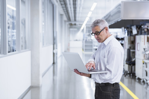 Manager in der Werkstatt einer Fabrik mit Laptop, lizenzfreies Stockfoto