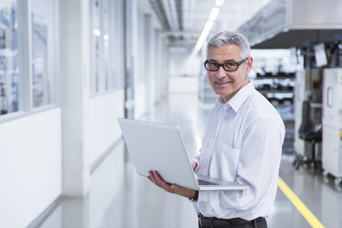 Manager in der Werkstatt einer Fabrik mit Laptop, lizenzfreies Stockfoto