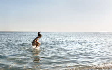 Spain, Menorca, girl jumping in the sea - MGOF03157