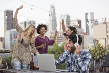 People dancing at rooftop party, with DJ using laptop - WESTF22831