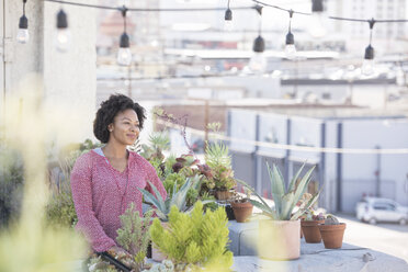 Smiling woman standing in her rooftop garden - WESTF22832