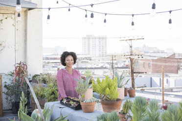 Smiling woman standing in her rooftop garden - WESTF22834