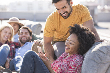 Freunde feiern eine Dachterrassenparty und benutzen einen Smart-Phone - WESTF22846