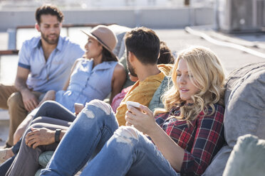 Freunde feiern eine Dachterrassenparty und benutzen einen Smart-Phone - WESTF22847