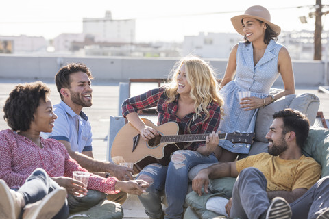 Freunde feiern eine Dachterrassenparty und spielen Gitarre, lizenzfreies Stockfoto