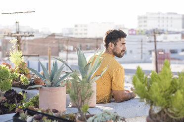 Junger Mann sitzt auf einer Dachterrasse - WESTF22870