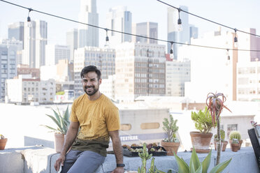 Young man sitting on rooftop terrace - WESTF22872