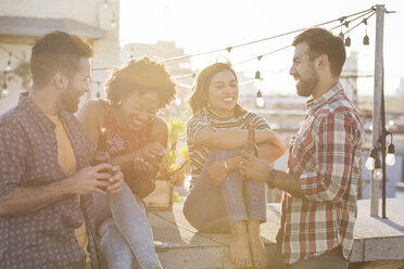 Friends having a rooftop party, chatting and drinking beer - WESTF22881