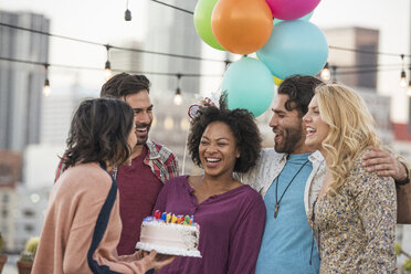 Friends celebrating birthday party on rooftop with birthday cake - WESTF22897