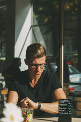 Mann sitzt in einem Café und schaut auf seine Uhr - CHAF01824