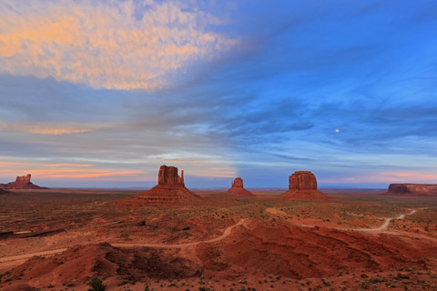 USA, Colorado Plateau, Utah, Arizona, Navajo Nation Reservation, Monument Valley, Sentinel Mesa, West Mitten Butte, East Mitten Butte and Merrick Butte at dawn with full moon stock photo