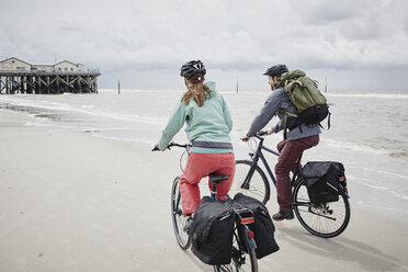 Germany, Schleswig-Holstein, St Peter-Ording, couple riding bicycle on the beach - RORF00709