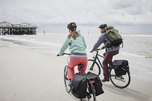 Deutschland, Schleswig-Holstein, St. Peter-Ording, Paar fährt Fahrrad am Strand - RORF00709