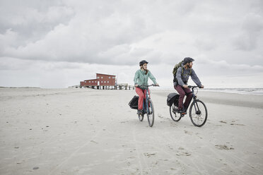 Germany, Schleswig-Holstein, St Peter-Ording, couple riding bicycle on the beach - RORF00727