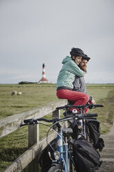 Germany, Schleswig-Holstein, Eiderstedt, couple on bicycle trip having a break near Westerheversand Lighthouse - RORF00751