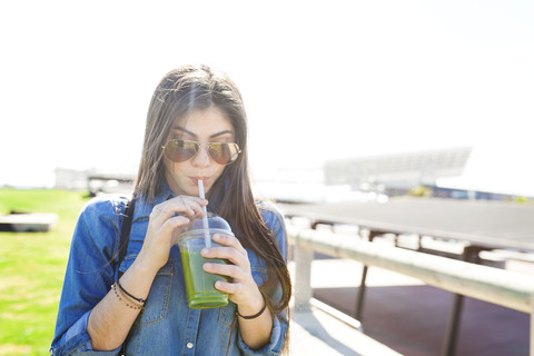 Spain, Barcelona, young woman drinking green beverage stock photo
