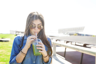 Spain, Barcelona, young woman drinking green beverage - VABF01269