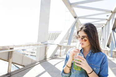 Spain, Barcelona, young woman with beverage on a bridge - VABF01275