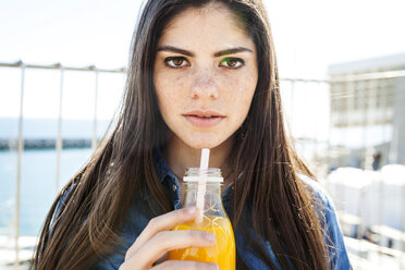 Porträt einer jungen Frau mit Glasflasche mit Orangensaft - VABF01279