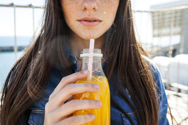 Young woman with bottle of orange juice, partial view - VABF01280