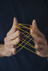 Close-up of man holding rubber bands - KNSF01200