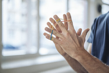 Close-up of man holding rubber bands - KNSF01201