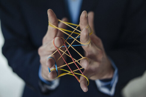 Close-up of businessman holding rubber bands - KNSF01204