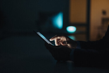 Nahaufnahme eines Geschäftsmannes, der spät im Büro arbeitet und ein Tablet benutzt - KNSF01211