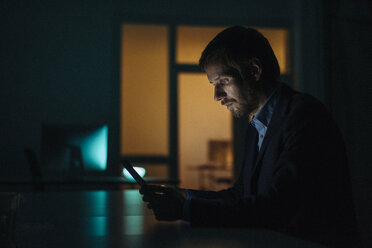 Businessman working late in office using tablet - KNSF01212