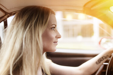 Lächelnde blonde Frau fährt Auto - DMOF00005