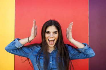 Portrait of screaming young woman in front of colourful wall - VABF01292