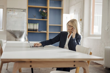 Geschäftsfrau mit Laptop und Mobiltelefon im Büro - JOSF00704