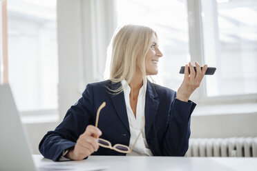 Businesswoman using cell phone in office - JOSF00705