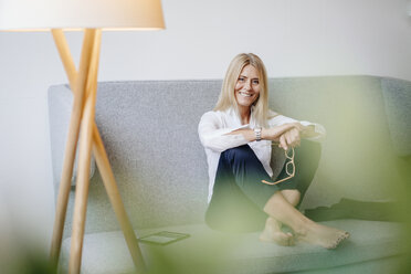 Portrait of smiling relaxed businesswoman sitting on couch - JOSF00714