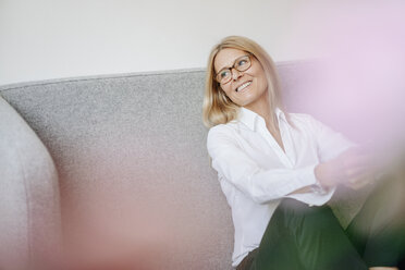 Smiling relaxed businesswoman sitting on couch - JOSF00716