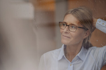 Businesswoman behind rainy windowpane looking away - JOSF00726