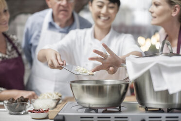 Participants in cooking class watching female chef cooking - ZEF13517