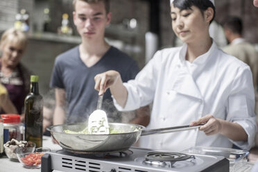 Teilnehmerin eines Kochkurses sieht einer Köchin beim Kochen zu - ZEF13542