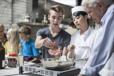 Female chef and students cooking in cooking class - ZEF13543