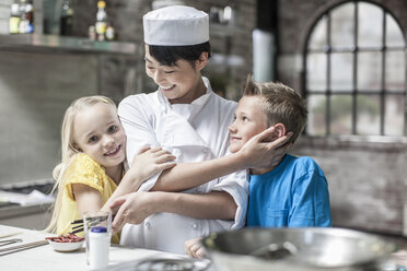 Female chef with happy boy and girl in cooking class - ZEF13550