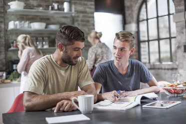 Father and son with book at dining table - ZEF13556