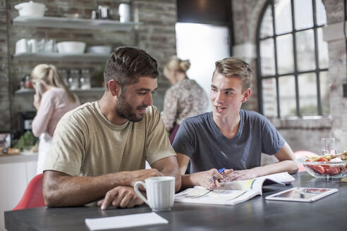 Father and son with book at dining table - ZEF13556