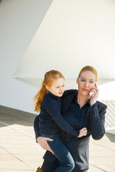 Businesswoman on the phone holding daughter - CHAF01837
