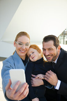 Lächelnder Geschäftsmann und Geschäftsfrau mit Mädchen, die ein Selfie machen - CHAF01844