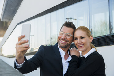 Smiling businessman with woman taking a selfie - CHAF01863