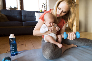 Mother with baby exercising with dumbbell at home - HAPF01372