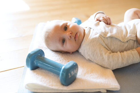 Baby zu Hause auf Matte neben Hanteln liegend - HAPF01375