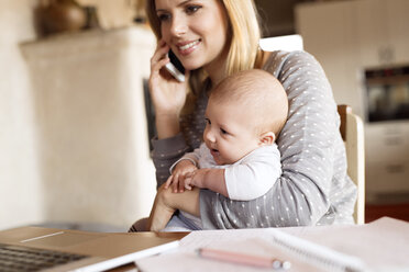 Lächelnde Mutter mit Baby zu Hause am Telefon - HAPF01388