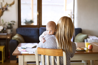 Mother with baby at home sitting at table - HAPF01392