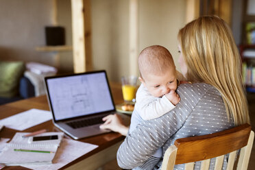 Mother with baby at home using laptop - HAPF01393